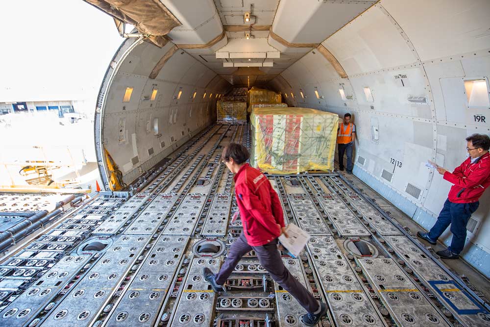 Hyun Chang Kim, station manager for Asiana Airlines, Inc., walks across the deck of a Boeing 747 cargo jet while the first of several Pacific Northwest cherries containers are loaded into the aircraft. Kim ensures all fruit is securely loaded by his crew that will largely be filled with cherries bound for markets in Korea. (TJ Mullinax/Good Fruit Grower)