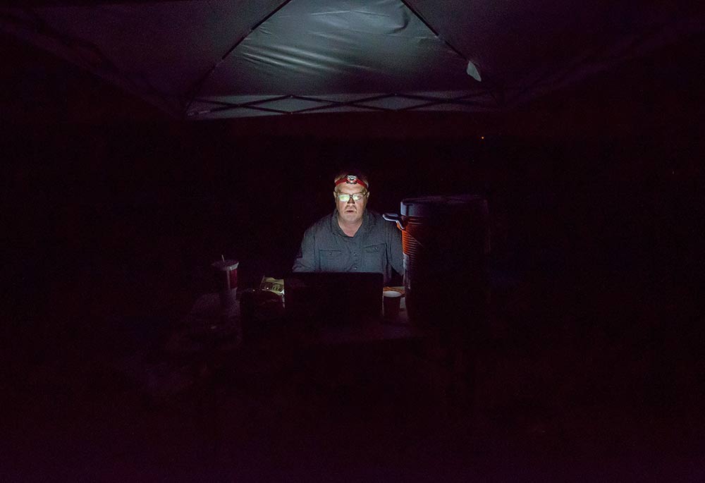 Collins closely monitors frequently changing smoke levels within his trial enclosure about 10:30 p.m. July 28, 2016. Sensors set up throughout the enclosure, in the smoker and outside of the enclosure provided a minute-by-minute appraisal of air quality conditions. <b> (TJ Mullinax/Good Fruit Grower)</b>