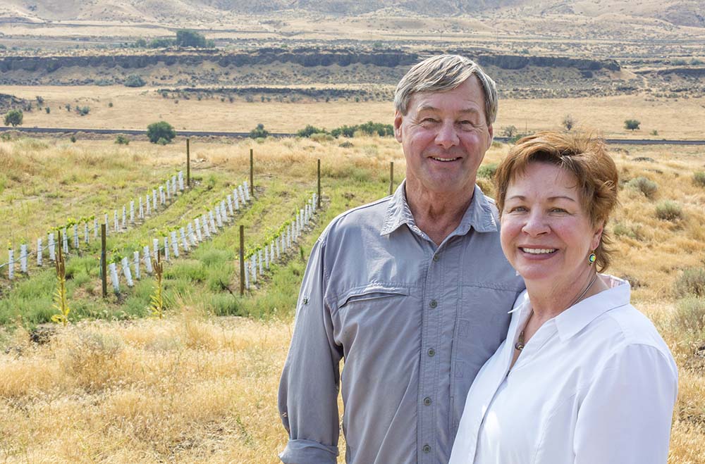 Larry and Jane Pearson stand in front of one of the small plots of Aglianico they planted at their new Badlands Vineyard. The grape is a dark red originating from the Campania and Basilicata region in southern Italy. At top, the view of the vineyard along southeast Washington’s Yakima River. <b>(TJ Mullinax/Good Fruit Grower)</b>