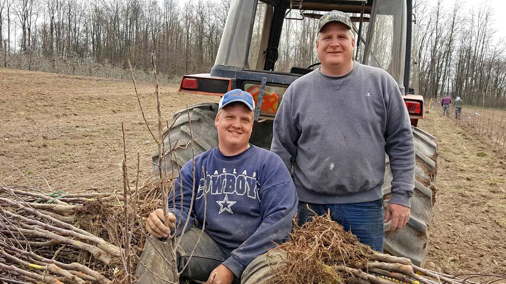 Twin Bee Orchard co-owner Tony Blattner and his son Nathan, left, take a break while planting 4,600 Smitten trees in spring 2016. Twin Bee, in west-central Michigan, has 135 acres of apples, including Gala, Red Delicious, Fuji, Honeycrisp, McIntosh, Empire, Ida Red and Jonagolds. <b>(Courtesy Twin Bee Orchard LLC.)</b>