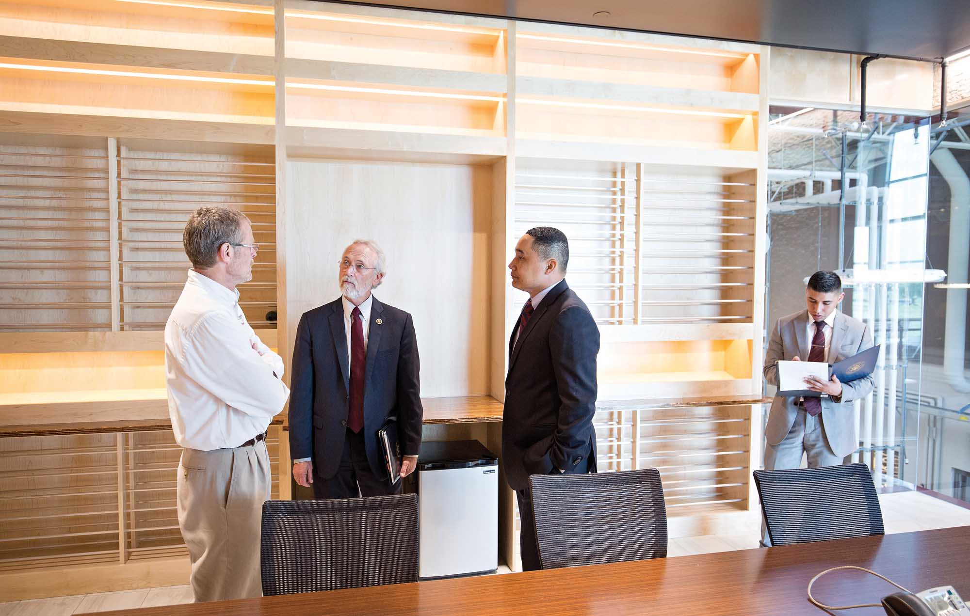 Thomas Henick-Kling, left, talks with U.S. Rep. Dan Newhouse, center left, on May 4, 2015, during a tour of the new Washington State University Wine Science Center. This room is the wine library room for meetings and tastings. (TJ Mullinax/Good Fruit Grower)