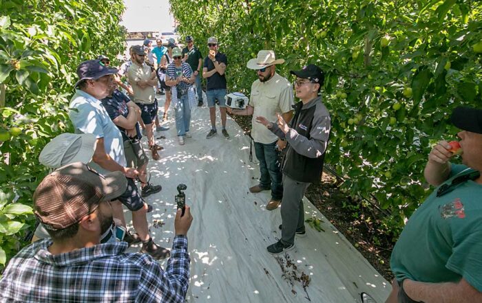 Charlie Wu of Orchard Robotics, center right, talks about the company’s latest vision system in Zillah, Washington, with a tour group from the Netherlands visiting Washington farms during a Washington Tree Fruit Research Commission educational exchange tour on July 9. (TJ Mullinax/Good Fruit Grower)